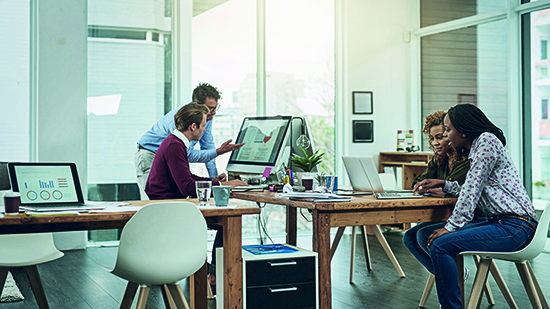 Co-workers in an open plan office looking at their laptops and computers